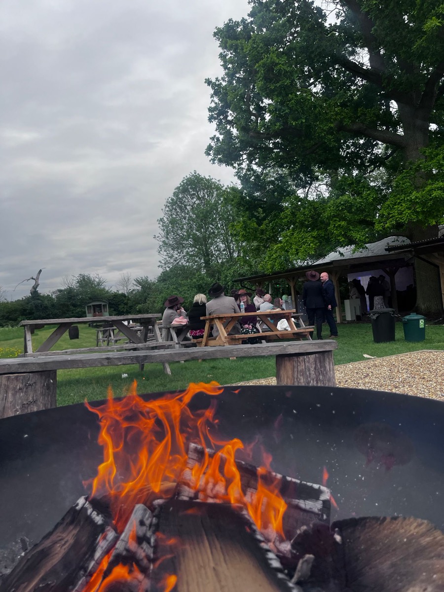 Guests gathered round the fire pit at picnic benches in the evening