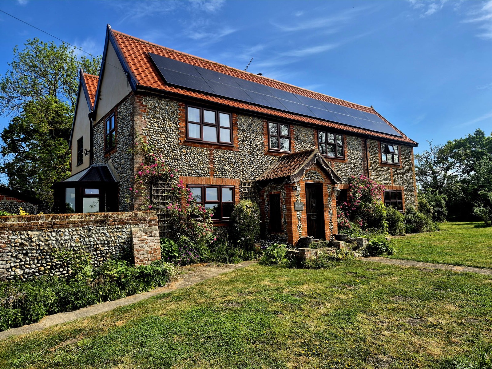 The Flint Hall family home — flint walls, red tile roof, summer garden