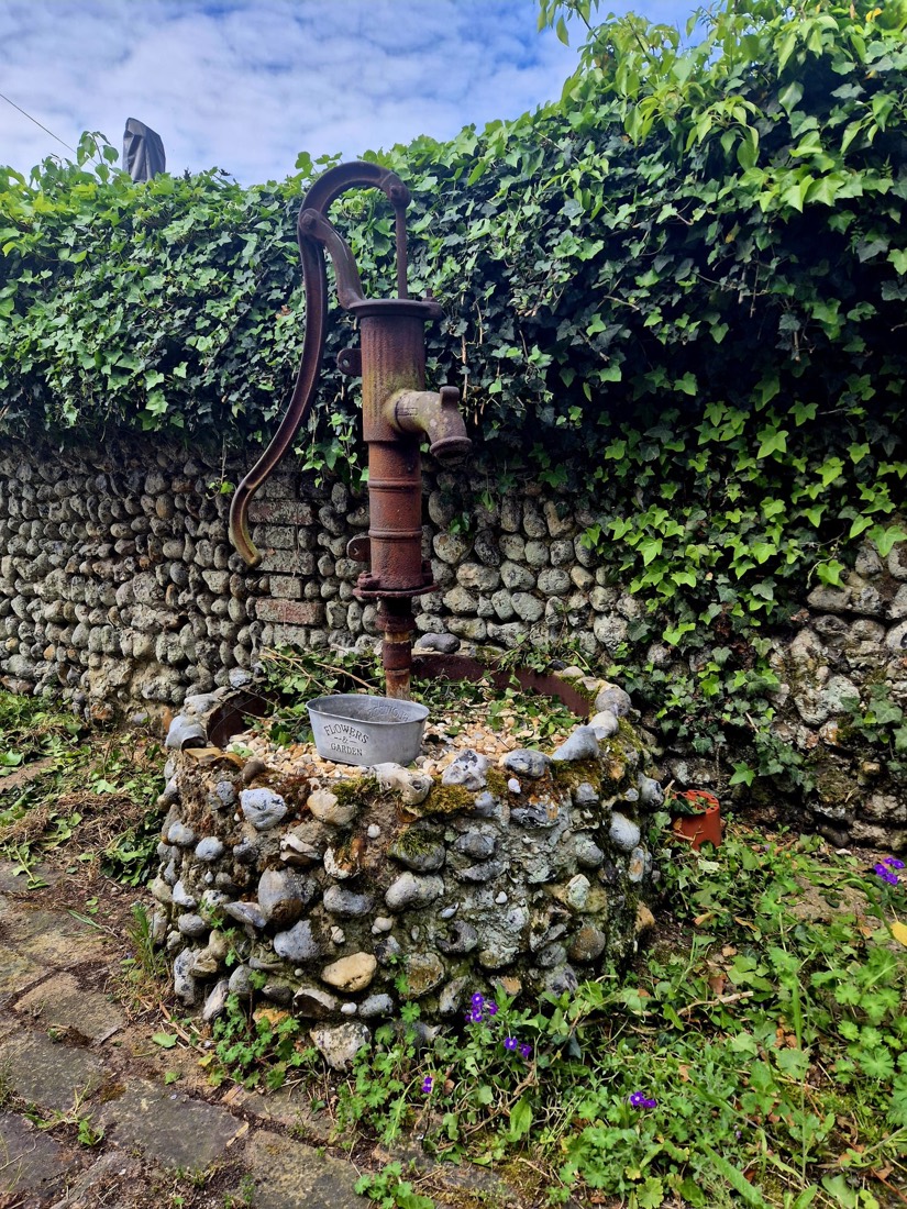 The original hand-pump beside the house, set in a stone surround