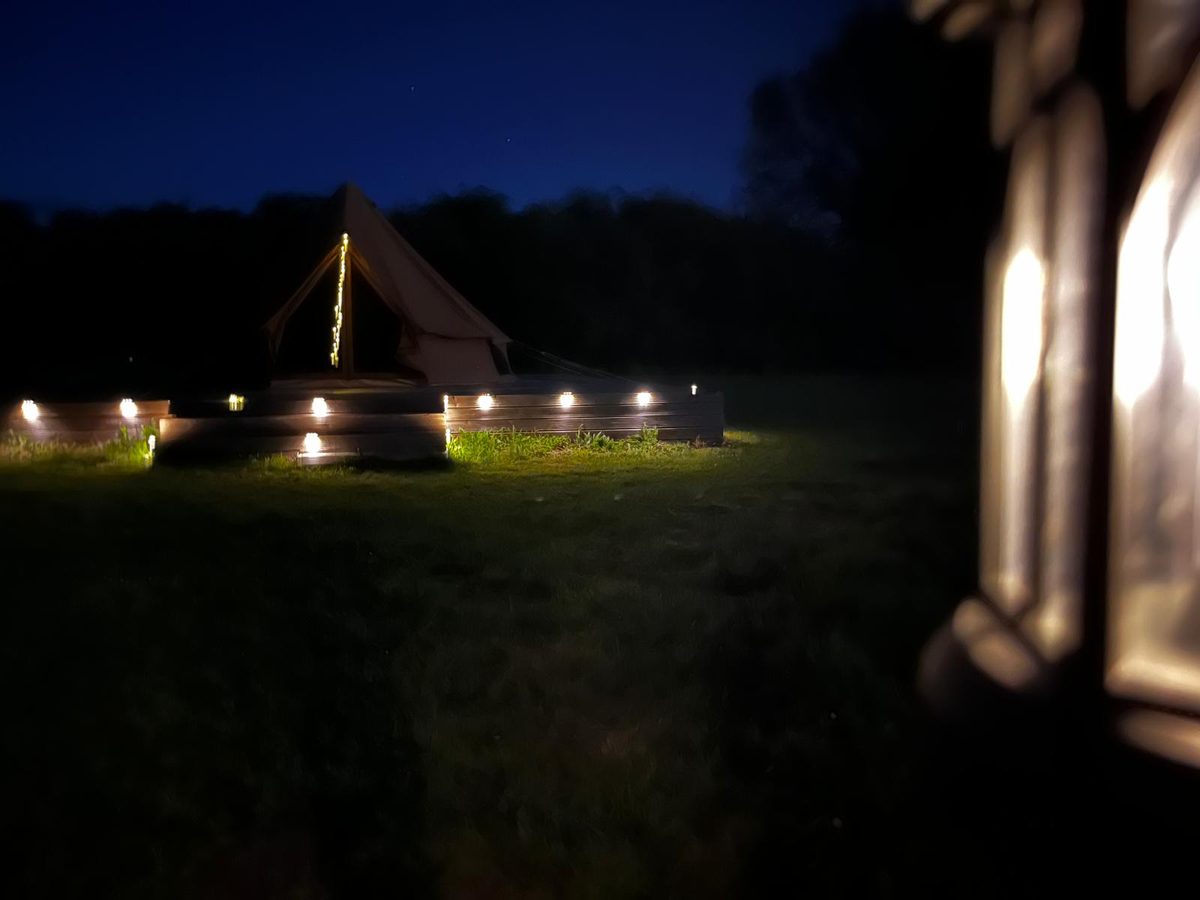Bell tent under stars with lantern path